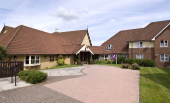 a modern , two - story building with a brown roof and white trim , surrounded by lush greenery and flowers at Premier Inn Bristol East (Emersons Green)