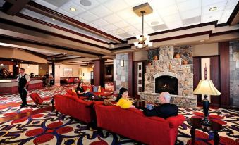 a man and a woman are sitting on red couches in a hotel lobby , enjoying each other 's company at Cherokee Casino West Siloam Springs Resort