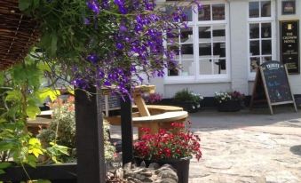a garden with a variety of colorful flowers and plants , including a purple tree in the foreground at The Crown Hotel