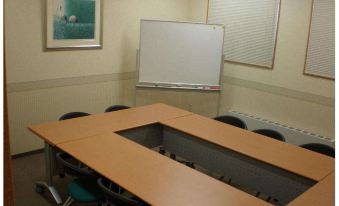 a conference room with a whiteboard , chairs , and tables set up for a meeting or presentation at Toyoko Inn Aizuwakamatsu Ekimae