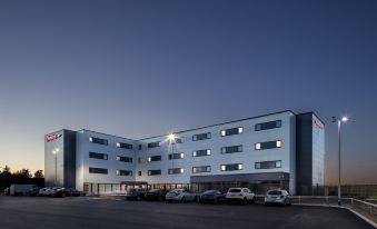 a large building with multiple stories , located in a parking lot at dusk at Hampton by Hilton Humberside Airport