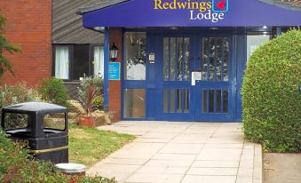 "a blue building with a sign that says "" redwings lodge "" is shown in front of a brick building" at Redwings Lodge Rutland