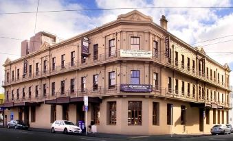 a city street with a brick building on the corner , surrounded by cars and other buildings at The Cambridge Hotel