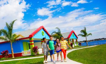 a group of children , including a boy and three girls , are posing for a picture in front of a colorful building at Legoland Beach Retreat