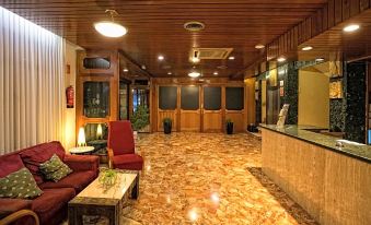 a spacious lobby with wooden walls , marble floor , and red seating arrangements , as well as a reception desk and large windows at Hotel Odon