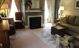 a living room with a fireplace , couch , and chairs is shown in the image at PineCrest Inn