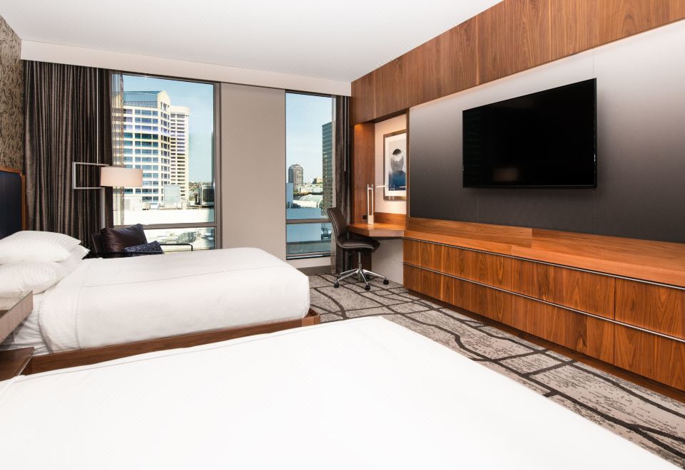 a modern hotel room with two beds , a flat screen tv , and large windows offering views of the city at The Charter Hotel Seattle, Curio Collection by Hilton