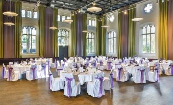 a large , elegant dining room with multiple tables set up for a formal event , possibly a wedding reception at Steigenberger Braunschweig