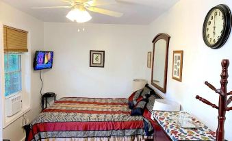 a clean and well - organized bedroom with a double bed , a dresser , and a tv mounted on the wall at Micosta Leisure Inn