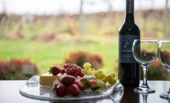 a wine bottle and a glass filled with red wine are sitting on a table next to a plate of grapes and cheese at De'Vine Escape