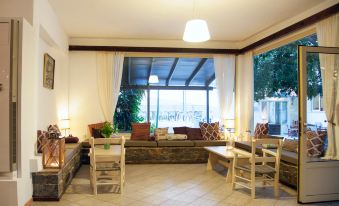 a large , open room with wooden furniture and a stone wall features a view of trees at Elpida Village