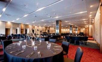 a large banquet hall with multiple round tables and chairs , all set for a formal event at Crowne Plaza Hobart, an IHG Hotel