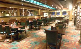 a large restaurant with multiple dining tables and chairs , as well as a bar area at Ute Mountain Casino Hotel