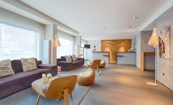 a modern living room with various furniture , including couches , chairs , and a dining table , arranged around the room at Hotel le Morgane