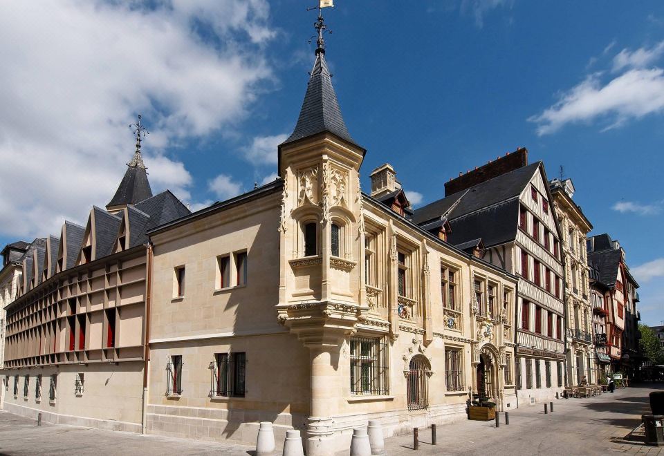 a traditional european building with a spire and flags on top , set against a blue sky at Hotel de Bourgtheroulde, Autograph Collection