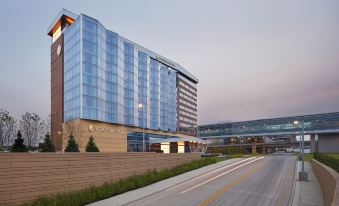 a modern building with a large glass facade and a curved roof is situated near a highway at InterContinental Hotels Minneapolis - ST. Paul Airport