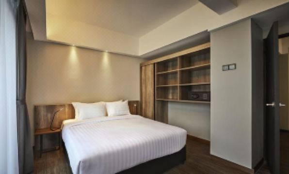 a large bed with white sheets is in a room with wooden shelves and lights at Tropics Eight Suites