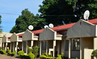 a row of two - story houses with satellite dishes on their roofs , located next to trees at Riverside Apartments