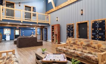 a spacious living room with wooden walls , hardwood floors , and a blue accent wall , featuring a large couch , coffee table , and bookshelf at Mad River Lodge