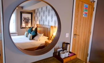 a modern bedroom with a large circular mirror above the bed , creating an eye - catching display at The Wheatsheaf Pub, Kitchen & Rooms