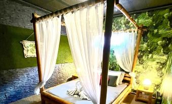 a wooden canopy bed with a white canopy is in a room with green walls and a tiled floor at Lovely