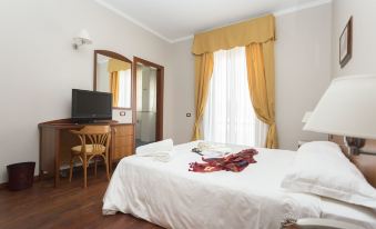 a neatly made bed with white sheets and a red blanket is in a room with wooden floors at Hotel Cavaliere