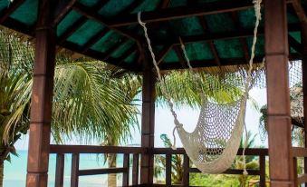 a hammock hanging from a wooden structure , situated near the ocean with palm trees in the background at Sea Horizon Resort