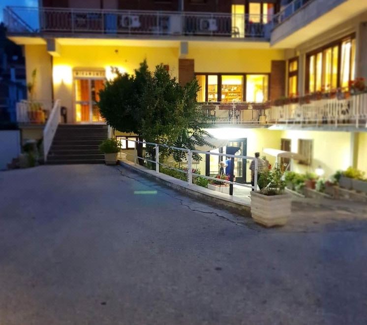 a modern apartment building at night , with the entrance lit up and a sign indicating that it is for sale at Hotel Miramonti