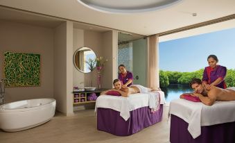 a woman and a man are receiving a massage in a spa setting , with a bathtub visible in the background at Memory Homestay Hue