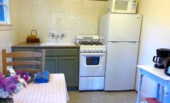 a kitchen with a refrigerator , oven , and microwave next to a dining table with a microwave at China Creek Cottages
