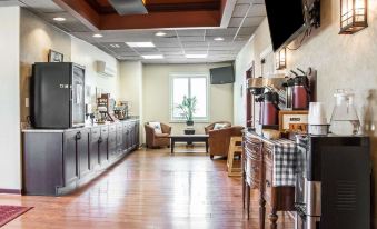 a well - lit restaurant with wooden floors , a bar area , and a dining table filled with cups and utensils at Island Inn & Suites, Ascend Hotel Collection