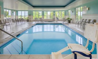 an indoor swimming pool surrounded by glass windows , allowing natural light to fill the space at Hilton Garden Inn Omaha West