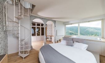 a bedroom with a large bed and spiral staircase leading to a balcony overlooking mountains at Villa Riviera Resort