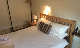 a neatly made bed with white sheets and a wooden headboard , accompanied by a lamp on the nightstand at The Sun Inn
