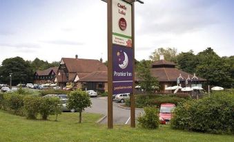 a large sign for a hotel is displayed in front of a building with cars parked nearby at Premier Inn Maidstone (West Malling) hotel