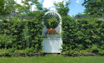 a garden with a white arbor surrounded by lush greenery and flowers , creating a picturesque setting at The White House Inn