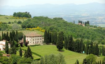 a large house surrounded by green grass and trees on a hillside , with a view of the surrounding landscape at Villa Campestri Olive Oil Resort