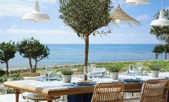 a dining table with chairs is set up on a patio overlooking the ocean , creating a serene atmosphere at Ikos Andalusia
