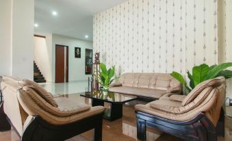 a modern living room with beige walls , black furniture , and a coffee table , along with a staircase in the background at RedDoorz Syariah Near Universitas Jenderal Soedirman