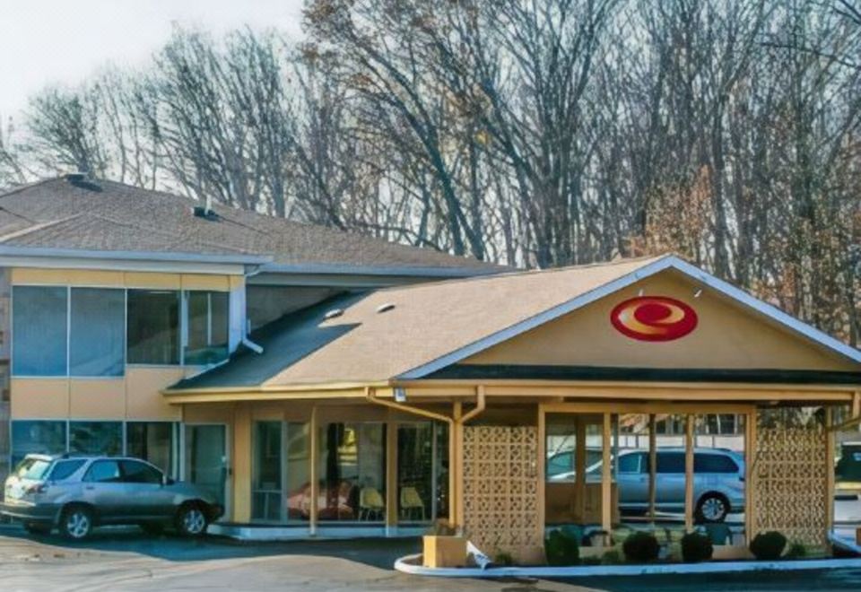 a building with a red circle on the front and cars parked outside , under a clear blue sky at Economy Inn & Suites