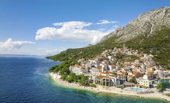 a picturesque coastal town with a large body of water in the background , surrounded by mountains at Tui Blue Makarska