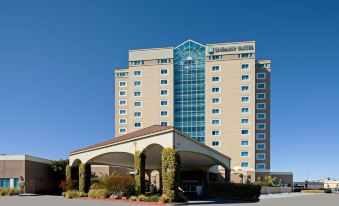 a large hotel building with many windows and a covered entrance , under a clear blue sky at Embassy Suites by Hilton Monterey Bay Seaside