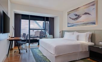 The elegant hotel features a bedroom with large windows, a white bed, and a desk in the middle at Element Kuala Lumpur