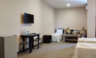 a room with two beds , a couch , and a tv . also a dining table in the room at Richmind Hotel