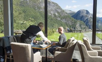 a man is sitting at a dining table in a restaurant , enjoying a meal with a waiter at Stalheim Hotel