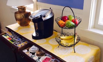 a table with a vase of flowers , a coffee maker , and a bowl of fruit at Spring Hill Inn