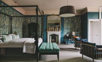 a modern bedroom with dark blue walls , wooden furniture , and a white canopy bed , along with a green upholstered bench at Hampton Manor
