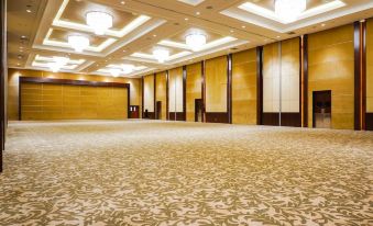 a large , empty banquet hall with beige walls and carpeted floor , illuminated by multiple lights at Swiss-Belhotel Serpong
