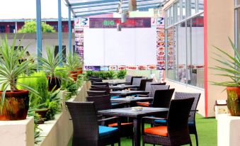 an outdoor dining area with several tables and chairs , as well as a tv mounted on the wall at Big Hotel