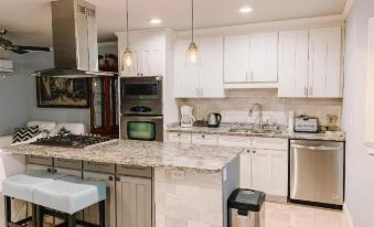 a clean and well - organized kitchen with white cabinets , stainless steel appliances , and a marble countertop at Park Place Inn and Cottages